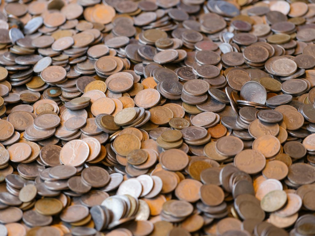 A large pile of mixed coins representing wealth and financial concepts.